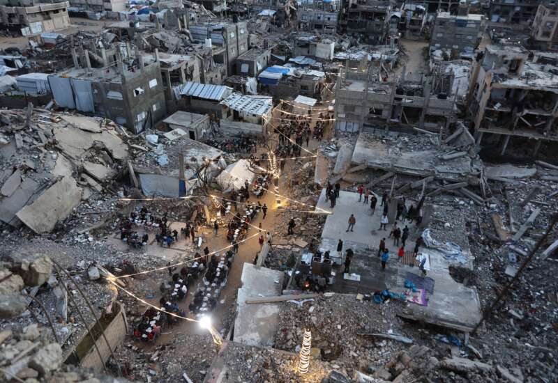 Displaced Palestinians gather for their fast-breaking iftar meal amid the rubble of destroyed buildings at the Jabalia refugee camp in the northern Gaza Strip, during the Muslim holy fasting month of Ramadan, on February 23, 2026.