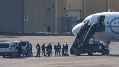 ICE agents look on as deportees are screened before boarding a GlobeX plane at Minneapolis-St. Paul International Airport on February 24, 2026, in Minneapolis, Minnesota.