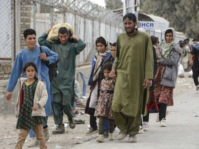 Afghan nationals walk near the Pul-e Abresham, or the Silk Bridge, after returning from Iran at the Afghanistan-Iran border crossing in Zaranj, Nimruz province, on March 2, 2026.