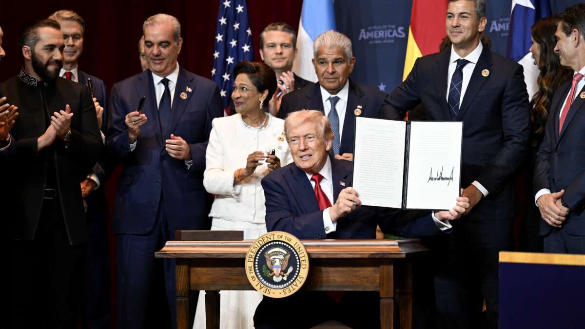 Donald Trump holds a document that indicates a U.S. "Commitment to Countering Cartel Criminal Activity" that he signed while surrounded by heads of state and government officials from 12 countries in the Americas as he hosts the “The Shield of the Americas Summit“ at the Trump National Doral Golf Club on March 7, 2026, in Doral, Florida. The White House describes the gathering as a landmark summit aimed at reshaping regional alliances and reinforcing U.S. influence in the Western Hemisphere.