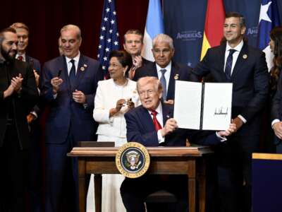 Donald Trump holds a document that indicates a U.S. "Commitment to Countering Cartel Criminal Activity" that he signed while surrounded by heads of state and government officials from 12 countries in the Americas as he hosts the “The Shield of the Americas Summit“ at the Trump National Doral Golf Club on March 7, 2026, in Doral, Florida. The White House describes the gathering as a landmark summit aimed at reshaping regional alliances and reinforcing U.S. influence in the Western Hemisphere.