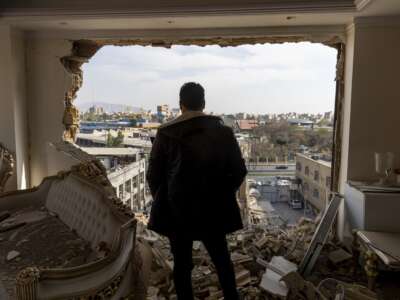 A man stands in a damaged residence at the site of buildings that were destroyed in an airstrike in the Khani Abad neighbourhood of Tehran, Iran, on March 14, 2026.