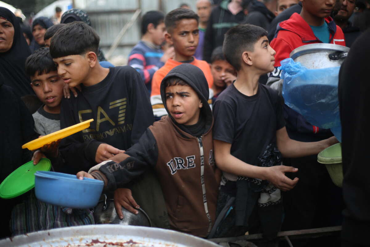 Displaced Palestinians gather to receive meals from a charity kitchen during Ramadan in the Nuseirat refugee camp, in the central Gaza Strip, on March 18, 2026.