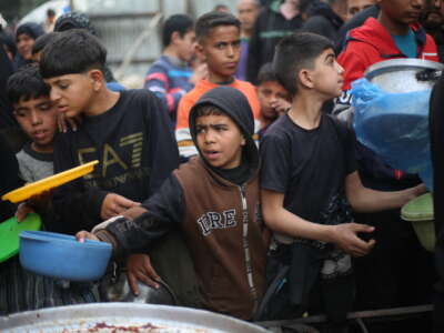 Displaced Palestinians gather to receive meals from a charity kitchen during Ramadan in the Nuseirat refugee camp, in the central Gaza Strip, on March 18, 2026.