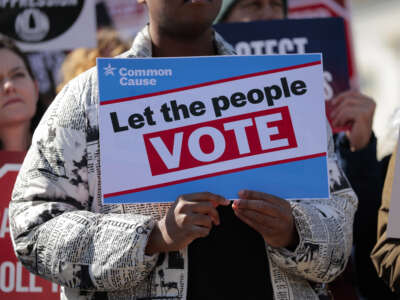 Attendees hold signs advocating for voting rights and against the SAVE America Act at a rally to outside the U.S. Capitol on March 18, 2026, in Washington, D.C.