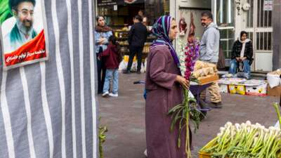 A woman carries flowers at a market as people prepare for Nowruz celebrations, on March 19, 2026, in Tehran, Iran.