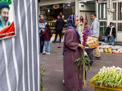 A woman carries flowers at a market as people prepare for Nowruz celebrations, on March 19, 2026, in Tehran, Iran.