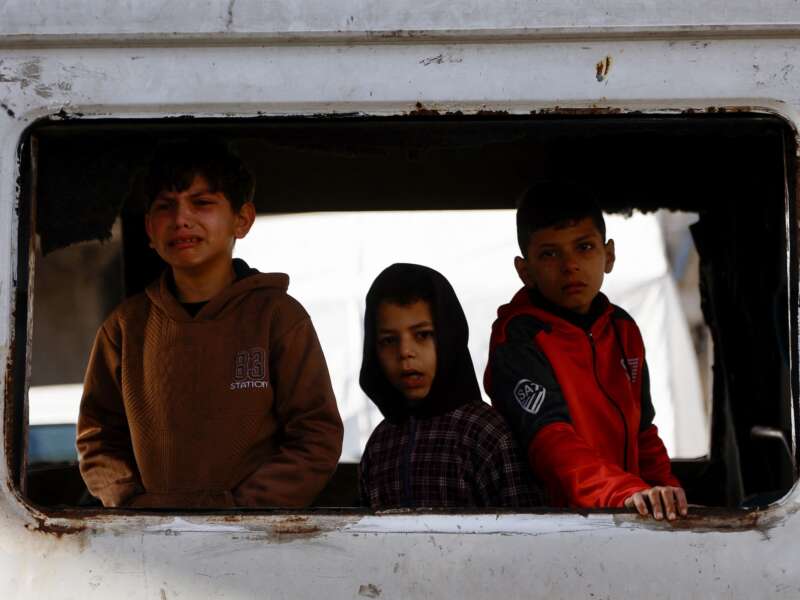 Children react as the bodies of Palestinian victims reportedly killed in Israeli strikes earlier in the day are transported at Al-Shifa Hospital in Gaza City on February 4, 2026.