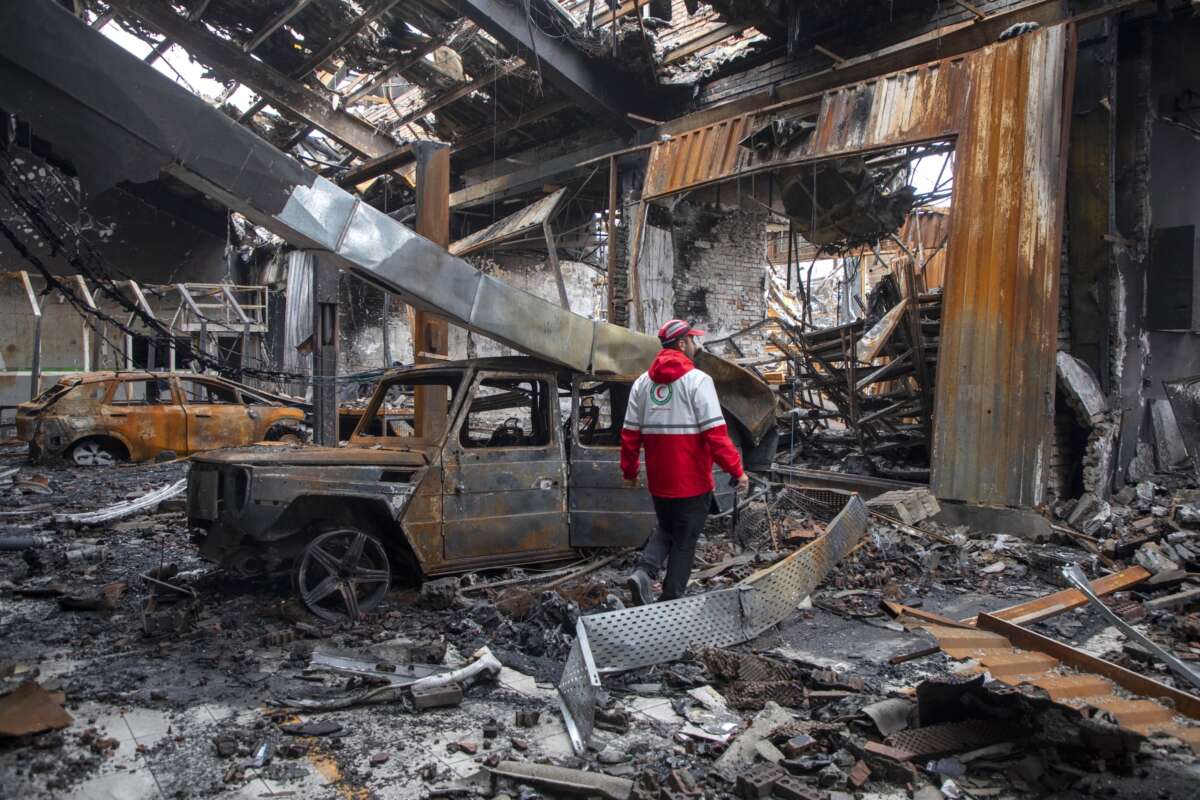 A worker with the Iranian Red Crescent Society walks through the rubble of a foreign car repair workshop that was destroyed during a joint U.S. and Israeli attack on March 28, 2026 in Tehran, Iran.
