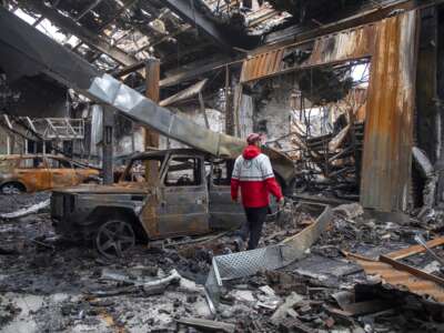 A worker with the Iranian Red Crescent Society walks through the rubble of a foreign car repair workshop that was destroyed during a joint U.S. and Israeli attack on March 28, 2026 in Tehran, Iran.