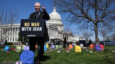 Sen. Chris Van Hollen (D-Maryland) speaks in front of a memorial made up of shoes and backpacks symbolizing those killed in the bombing of the Minab elementary school and other civilians killed in Iran sits outside the United States Capitol on March 18, 2026 in Washington, D.C.