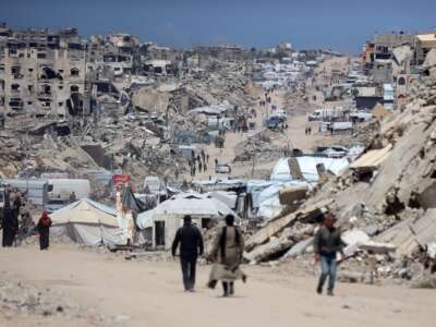 People walk past the rubble of destroyed buildings in the Jabalia camp for Palestinian refugees in the northern Gaza Strip on April 13, 2026.