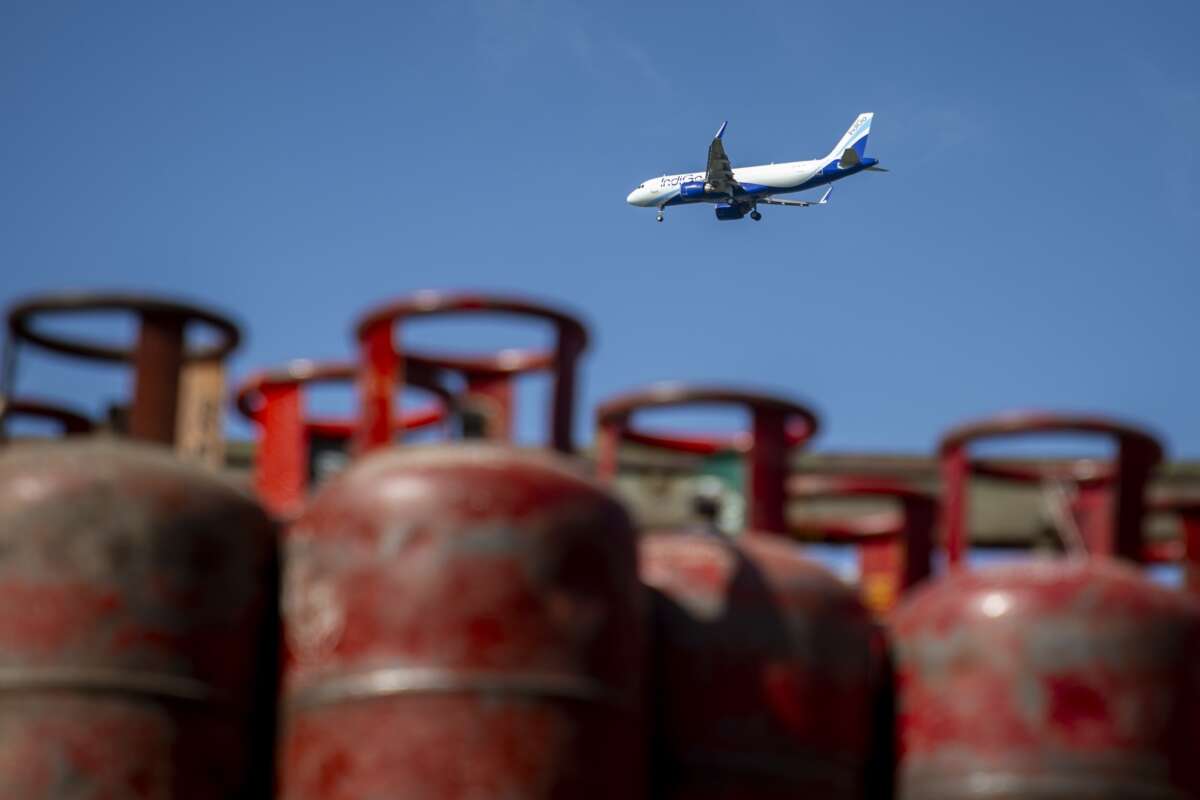 An IndiGo aircraft flies over empty liquefied petroleum gas cylinders at a gas agency amid a shortage of cooking gas on the outskirts of Srinagar, Indian-administered Kashmir.