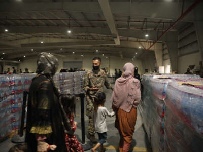 Culinary specialist Sgt. Juan Miranda with the 155th Combat Sustainment Support Battalion directs evacuees into the dining facility at Camp As Sayliyah on August 20, 2021, in Doha, Qatar.
