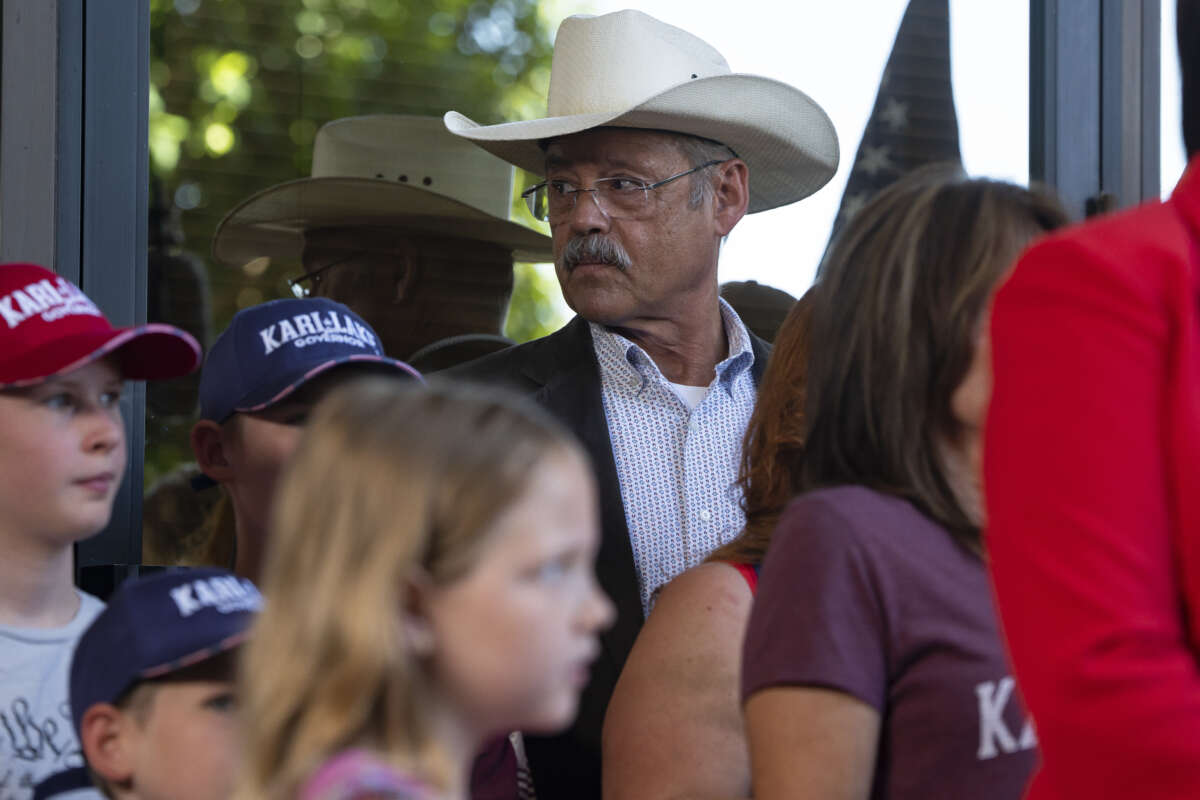 Mark Finchem listens as former Arizona Republican candidate for Governor Kari Lake holds a press conference the day after Maricopa County Superior Court Judge Peter A. Thompson dismissed Lake's final election loss claim on May 23, 2023, in Phoenix, Arizona.