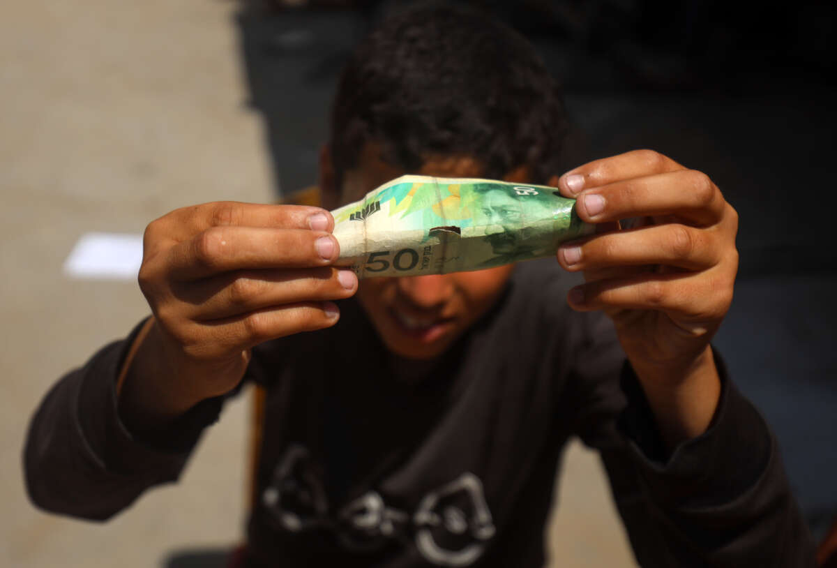 Palestinians rehabilitate and restore damaged and worn-out banknotes due to the halt in currency transfers from Israeli banks to Palestinian banks in Gaza City, on June 17, 2025.