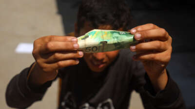 Palestinians rehabilitate and restore damaged and worn-out banknotes due to the halt in currency transfers from Israeli banks to Palestinian banks in Gaza City, on June 17, 2025.