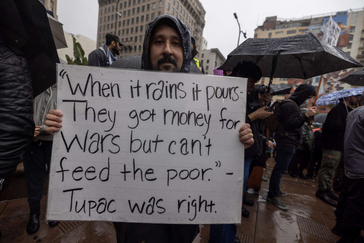 People participate in a "No War on Venezuela" protest in the rain on January 3, 2026, in Los Angeles, California.