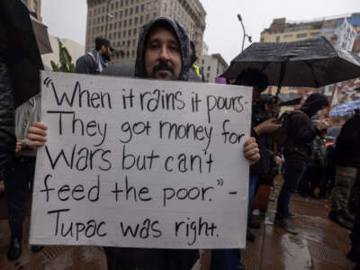 People participate in a "No War on Venezuela" protest in the rain on January 3, 2026, in Los Angeles, California.