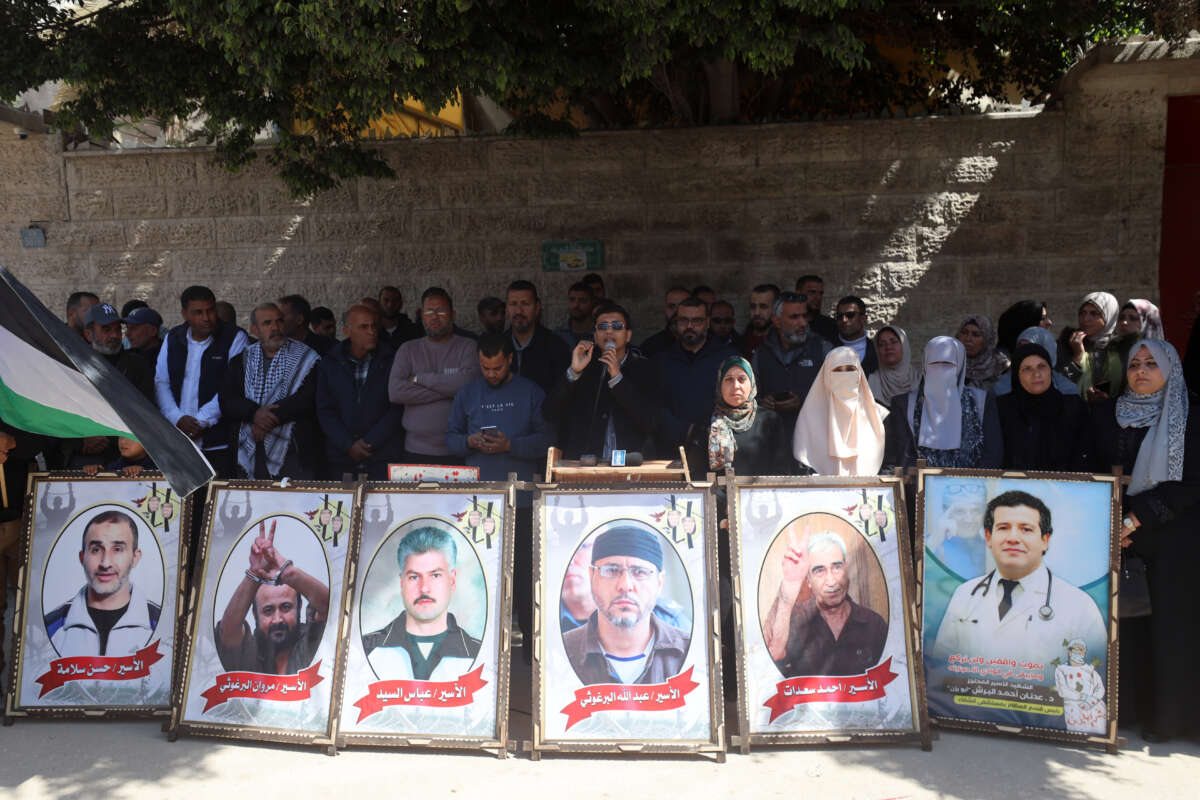 Protesters hold placards outside the Red Cross offices in Gaza City, on March 31, 2026, during a rally against a bill approved by Israel's parliament that would allow the execution of Palestinians.