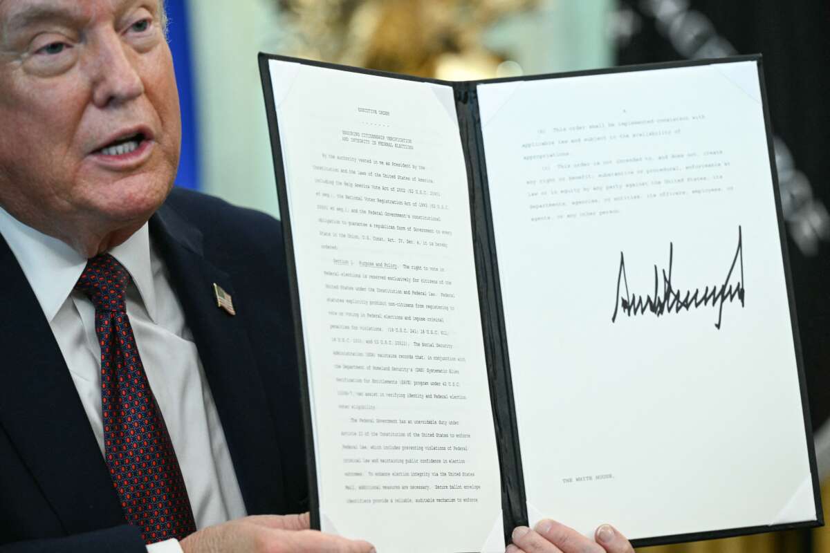 Donald Trump displays an executive order he signed cracking down on mail-in voting ahead of midterm elections, in the Oval Office of the White House, in Washington, D.C., on March 31, 2026.