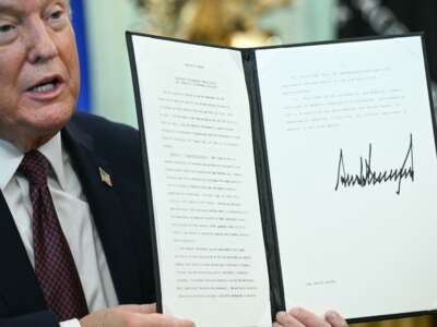 Donald Trump displays an executive order he signed cracking down on mail-in voting ahead of midterm elections, in the Oval Office of the White House, in Washington, D.C., on March 31, 2026.