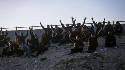 Spectators react as Palestinian players play football barefoot on a sandy field beneath Wadi Gaza Bridge, south of Gaza City, on March 30, 2026.