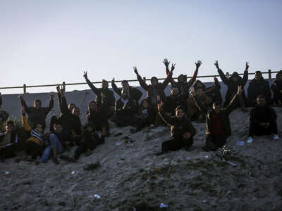 Spectators react as Palestinian players play football barefoot on a sandy field beneath Wadi Gaza Bridge, south of Gaza City, on March 30, 2026.