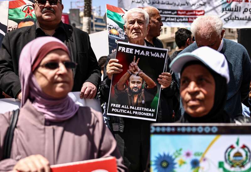 Palestinian demonstrators hold pictures of prisoners held in Israeli jails, including jailed Palestinian leader Marwan Barghouti, during a rally in Ramallah, in the occupied West Bank, on April 16, 2026, to mark Prisoners' Day and to protest against Israeli parliament's approval of a new death penalty bill for Palestinians.