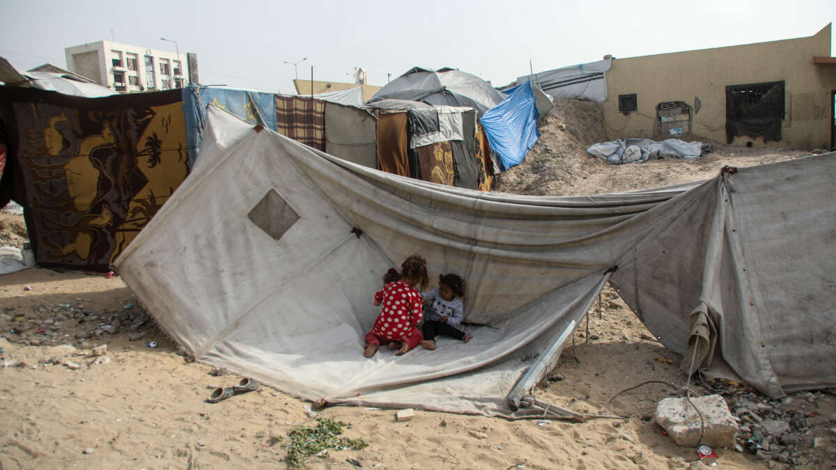 Children sit in front of a tent on April 18, 2026, in Gaza City, Gaza.