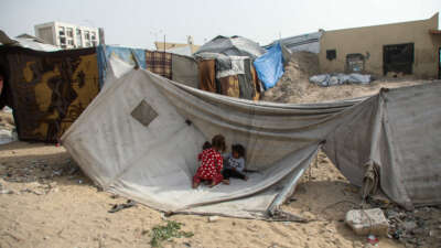 Children sit in front of a tent on April 18, 2026, in Gaza City, Gaza.