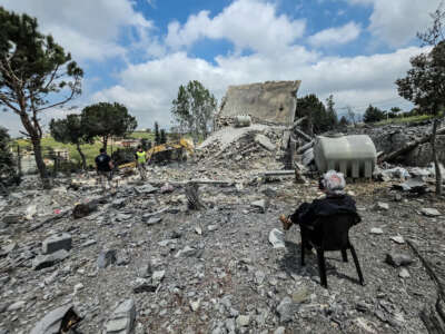 A man sits watching as Lebanese first responders search for human remains amongst the rubble the day after a house was targeted in an Israeli airstrike in the southern Lebanese city of Nabatieh, on May 1, 2026.