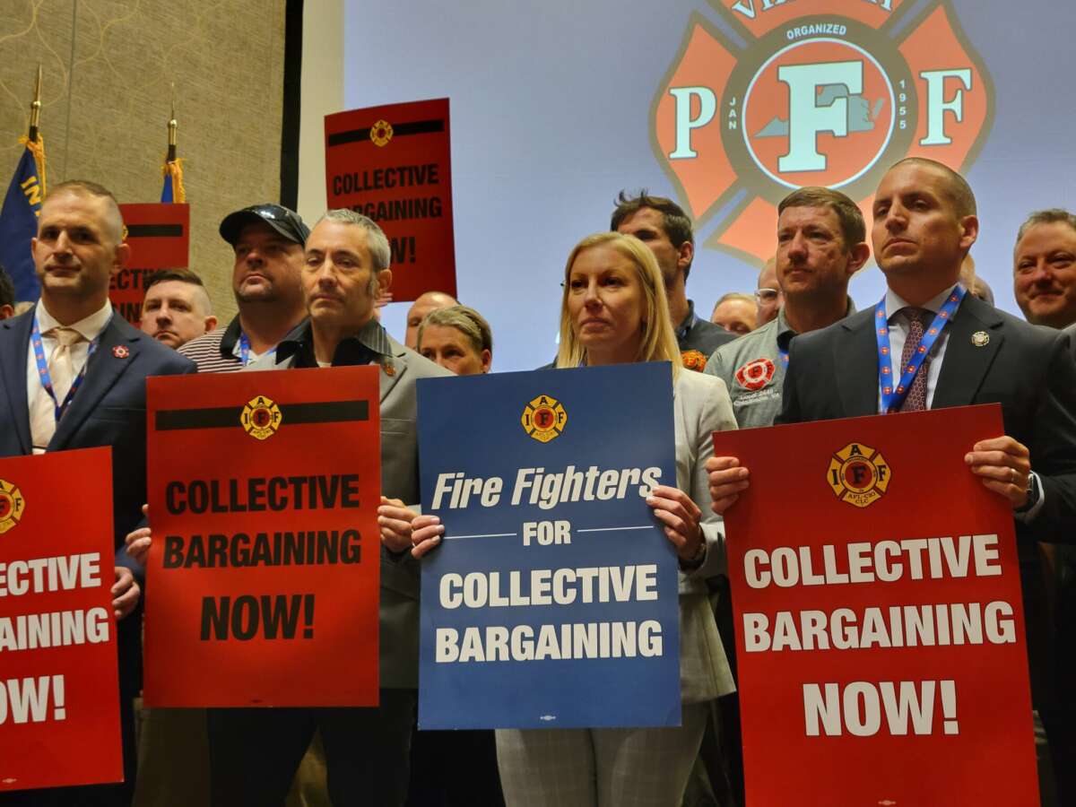 Members of Virginia Professional Firefighters association hold signs during their biannual convention to protest Gov. Abigail Spanberger’s veto of collective bargaining legislation.
