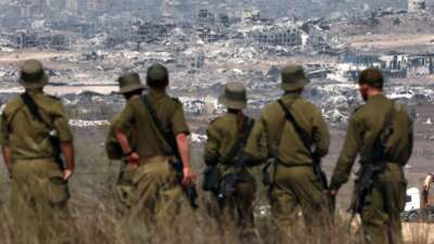 Israeli soldiers look at destroyed buildings in the Gaza Strip, on August 13, 2025.