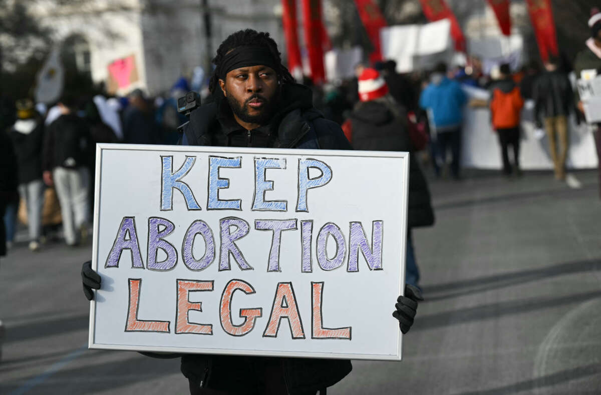 A man holds a sign reading "Keep Abortion Legal" as anti-abortion activists march in the 53rd annual March for Life rally in Washington, DC, on January 23, 2026.