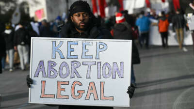 A man holds a sign reading "Keep Abortion Legal" as anti-abortion activists march in the 53rd annual March for Life rally in Washington, DC, on January 23, 2026.