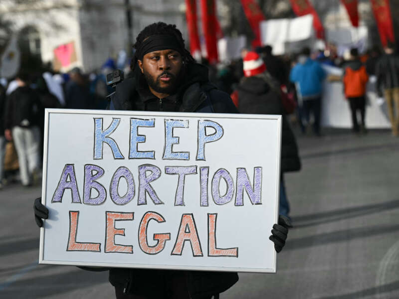 A man holds a sign reading "Keep Abortion Legal" as anti-abortion activists march in the 53rd annual March for Life rally in Washington, DC, on January 23, 2026.