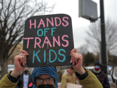 Protesters with Gender Liberation Movement and ACT UP block the entrance to the Department of Health and Human Services while protesting the Trump administration’s plan to cut federal funding to clinics providing care for transgender youth on February 17, 2026 in Washington, D.C.