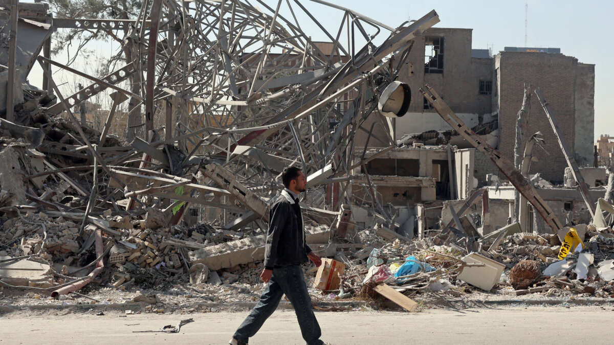 A man walks past destroyed buildings following U.S.-Israeli airstrikes in central Tehran on March 4, 2026.