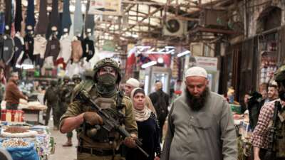 Palestinian shoppers walks past as Israeli soldiers patrol the market in the Old City of Nablus, in the northern Israeli-occupied West Bank, on April 27, 2026.