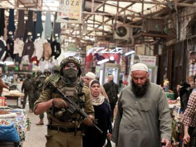 Palestinian shoppers walks past as Israeli soldiers patrol the market in the Old City of Nablus, in the northern Israeli-occupied West Bank, on April 27, 2026.