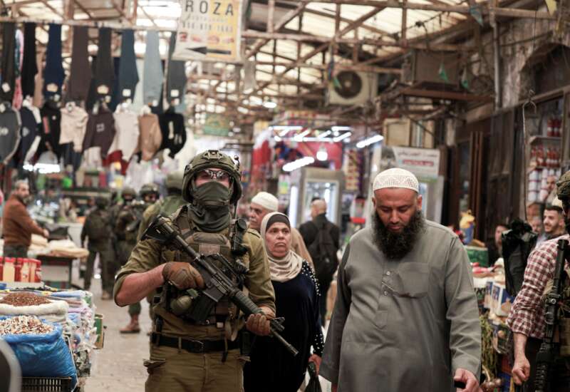 Palestinian shoppers walks past as Israeli soldiers patrol the market in the Old City of Nablus, in the northern Israeli-occupied West Bank, on April 27, 2026.