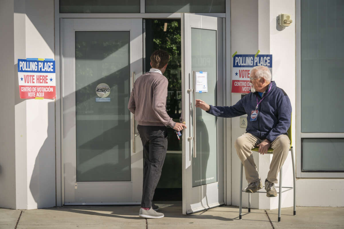 An election worker holds the door open for people casting their votes at the Washington-Liberty Annex polling location in Arlington, Virginia, on April 21, 2026.
