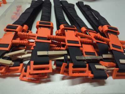 3D-printed tourniquets manufactured by the Distributed Medical Device Manufacturing collective (DMDM) are stacked on a table after a work party held in April 2026.