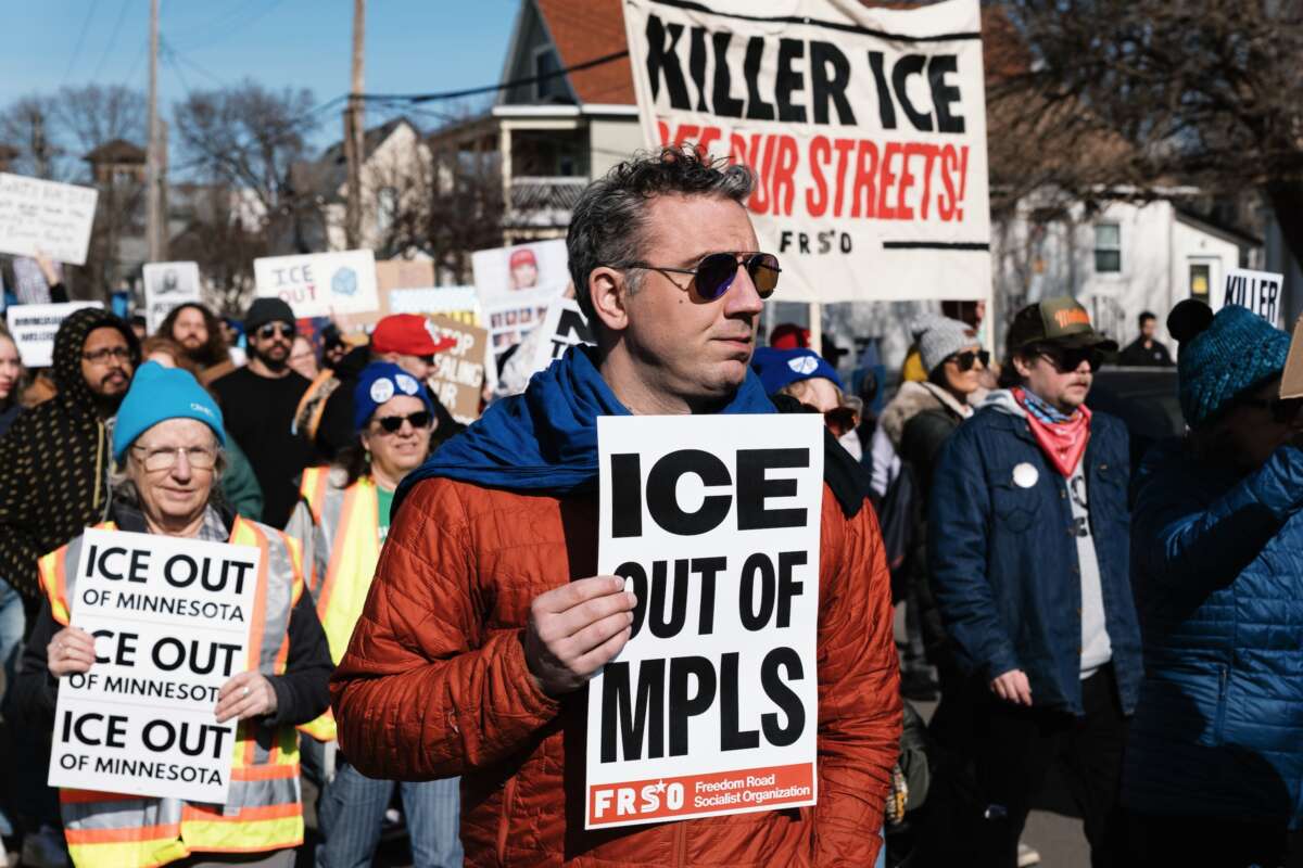 A demonstrator holds a placard reading ''ICE out of MPLS'' during a rally and demonstration organized by the Minnesota Immigrant Rights Action Committee (MIRAC) to demand justice for the Minneapolis community and its immigrants, and for the immediate departure of ICE, in Minneapolis, Minnesota, on February 15, 2026.