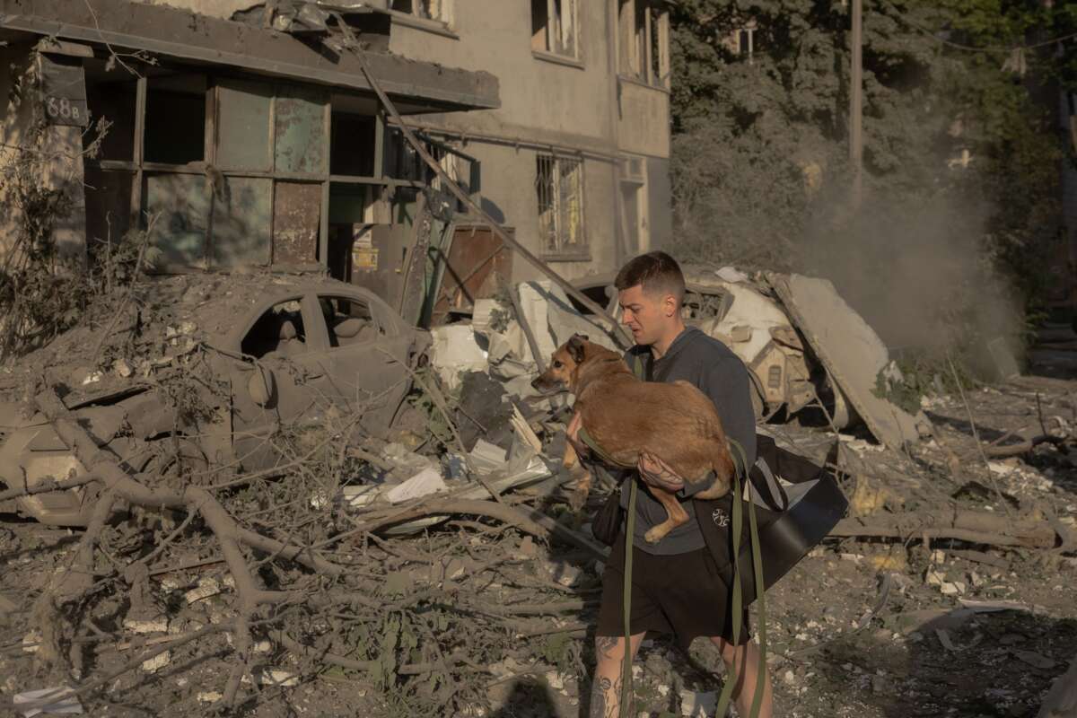 A man carries a dog in his arms outside a multi-story residential building that was damaged following Russian missile and drone strikes on Kyiv on June 2, 2026. Russia fired more than 600 drones and dozens of missiles in an overnight barrage on Ukraine.