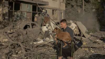 A man carries a dog in his arms outside a multi-story residential building that was damaged following Russian missile and drone strikes on Kyiv on June 2, 2026. Russia fired more than 600 drones and dozens of missiles in an overnight barrage on Ukraine.