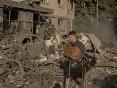 A man carries a dog in his arms outside a multi-story residential building that was damaged following Russian missile and drone strikes on Kyiv on June 2, 2026. Russia fired more than 600 drones and dozens of missiles in an overnight barrage on Ukraine.