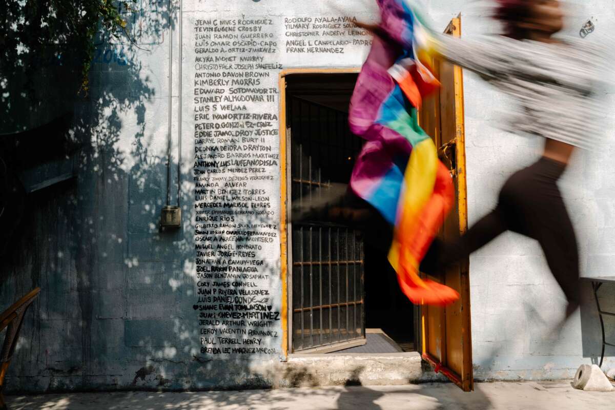 Kha'Dija Mendheim runs by holding a Pride flag in front of a Pulse nightclub memorial mural at Pridelines in Miami, Florida, on May 3, 2023.