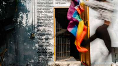Kha'Dija Mendheim runs by holding a Pride flag in front of a Pulse nightclub memorial mural at Pridelines in Miami, Florida, on May 3, 2023.